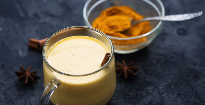 Indian spice turmeric Golden milk in a mug on a dark stone table
